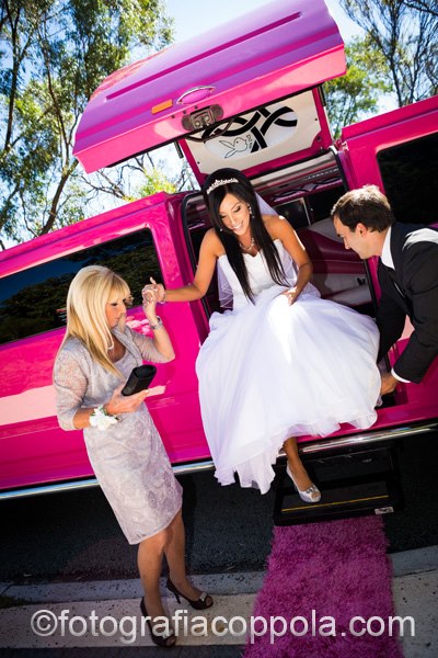 Perth Pink Hummer Limo Jet Door / Bridal Door Wedding Limousine with the chauffeur providing assistance to the bride as she steps out of the Hummer Wedding limousine.